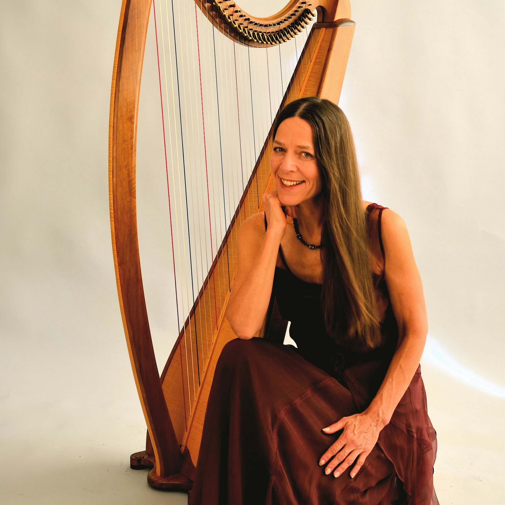 a smiling woman next to a harp